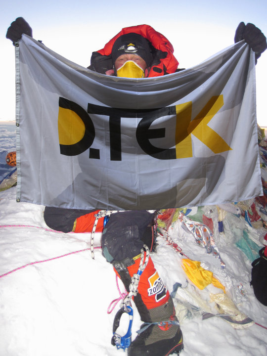 Виталий на вершине с флагом генерального спонсора экспедиции