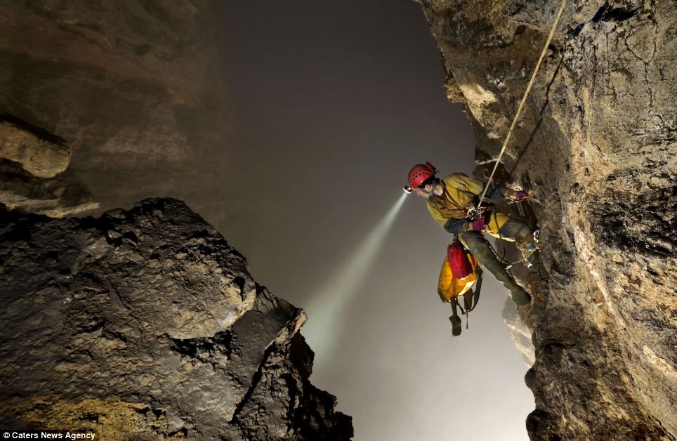 Американский спелеолог Erin Lynch всматривается вниз через плечо в гигантскую пустоту пещеры. Сейчас он находится в 250 метрах от пола огромного зала, и не может увидеть полностью весь его объем из-за густого облака.