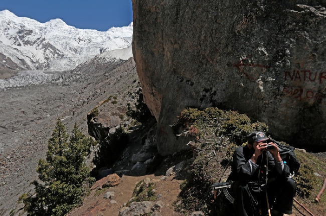 В это же время за безопасностью туристической группы следит вооруженный военный, осматривая в бинокль прилегающие дороги и горные склоны