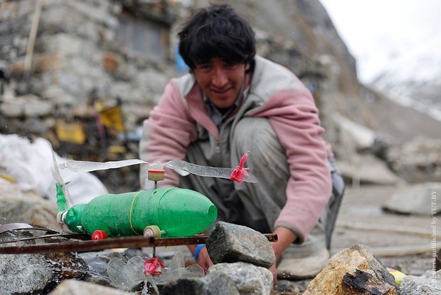 Носильщик смотрит на самодельный вертолет из пластиковых бутылок. В игрушку встроен водометный двигатель, работающий на талой ледниковой воде. Фото: Reuters / Wolfgang Rattay