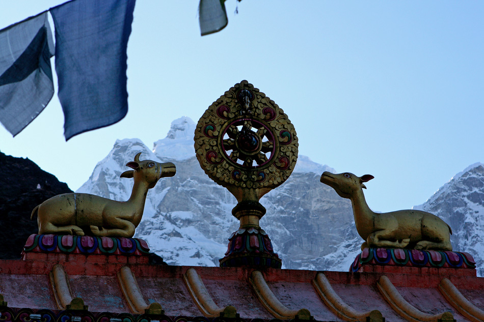 Колесо дхармы и олени на воротах. Видны также молитвенные флаги, на заднем плане шеститысячник Кангтега