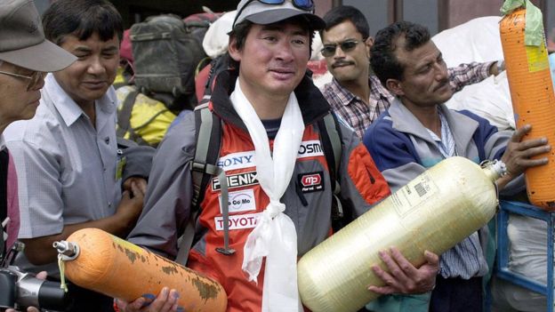 Японский альпинист с пустыми кислородными баллонами в руках в Катманду