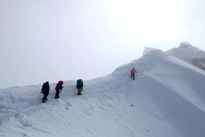 четверо альпіністів просуваються по сніжному хребту по добре протоптаній стежці в туманному ранку на схилі восьмитисячника Манаслу. Каззанеллі, праворуч у червоній куртці 