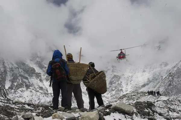 Місцеві носії спостерігають за приземленням гелікоптера у базовому таборі Евересту